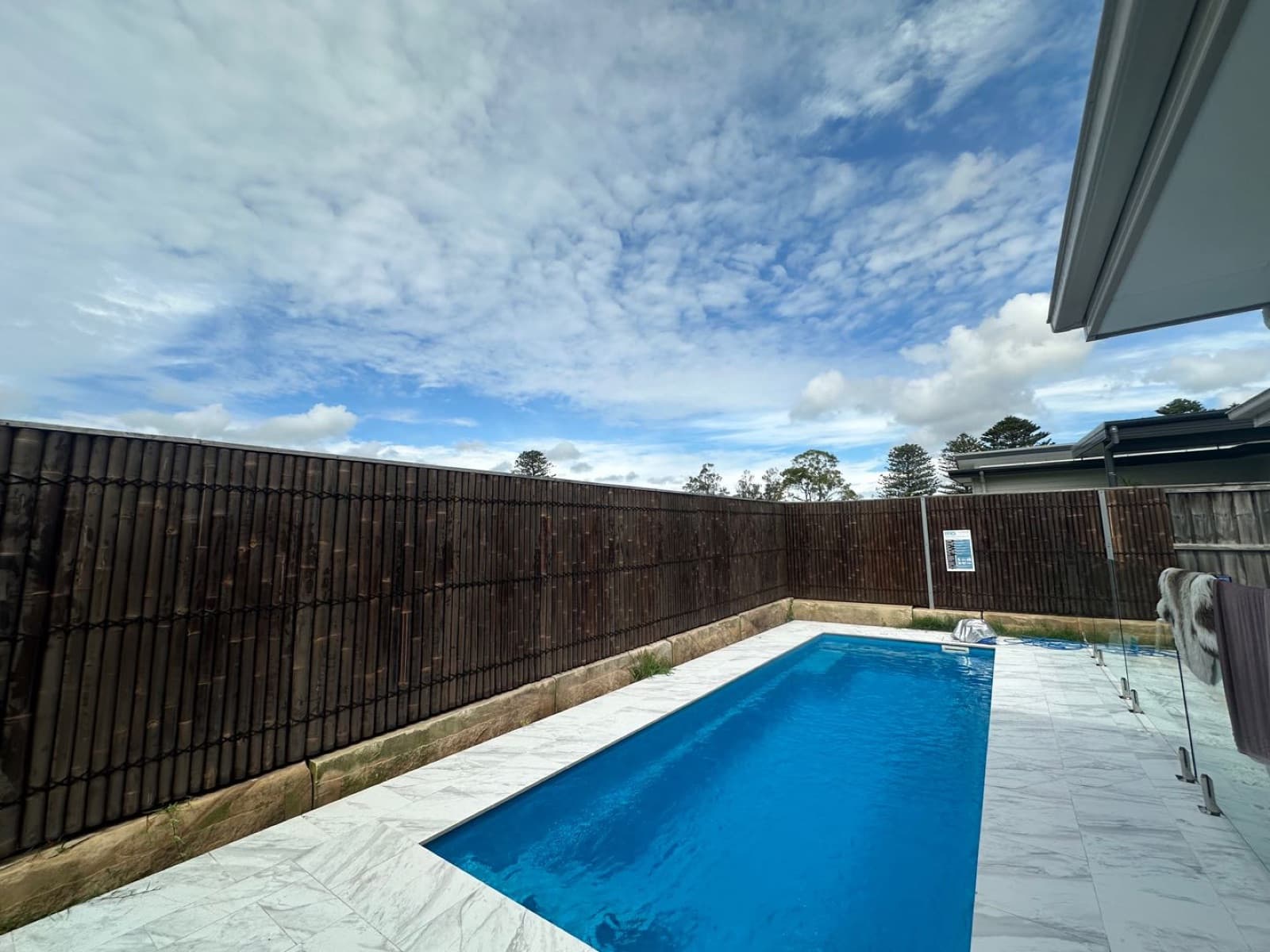Rectangular pool with sandstone surround and dark fencing